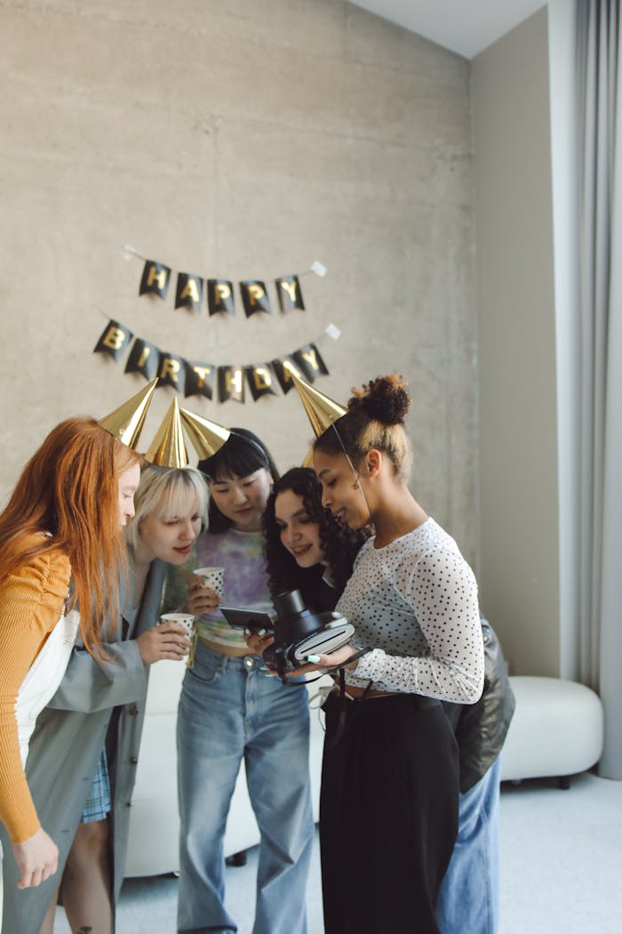 A joyful group of diverse friends celebrating a birthday indoors with party hats.